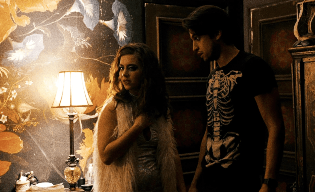 Two characters from Them Come Blood stand in a decorated room.
